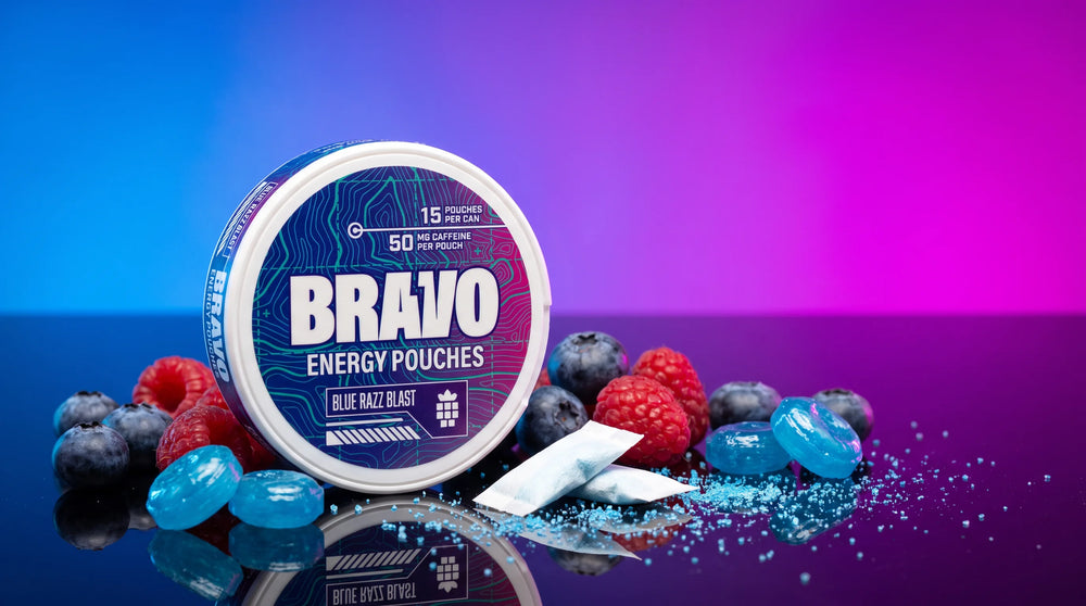 Bravo Blue Razz Blast caffeine pouch tin with blueberries, raspberries and blue raspberry candy on a dark glossy surface