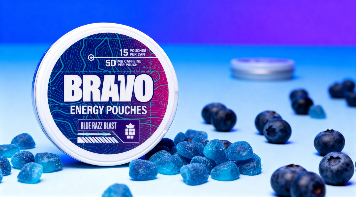 Bravo Blue Razz Blast caffeine pouch tin in sharp focus with blue raspberry candies and blueberries, one small unbranded tin blurred in the background — best nootropic caffeine pouches 2026 comparison hero