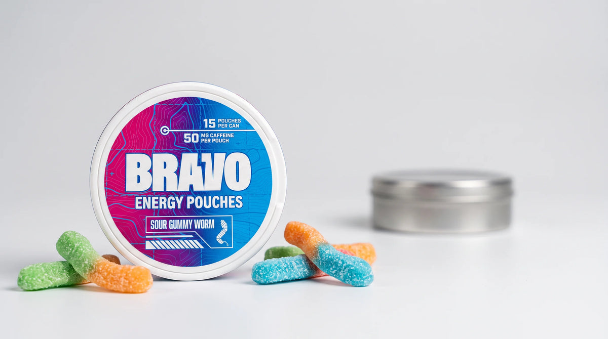 Bravo Sour Gummy Worm caffeine pouch can in sharp focus with sour gummy candies, and a generic unbranded competitor tin blurred in the background — Wip vs Bravo caffeine pouch comparison, July 2026