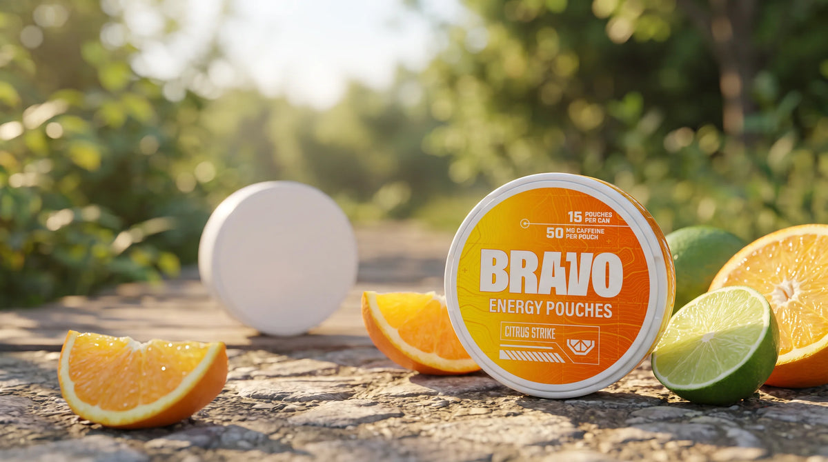 Bravo Citrus Strike caffeine pouch tin in sharp focus on a trail, with a plain unbranded competitor tin blurred in the background — CAFFYNE vs Bravo comparison hero.