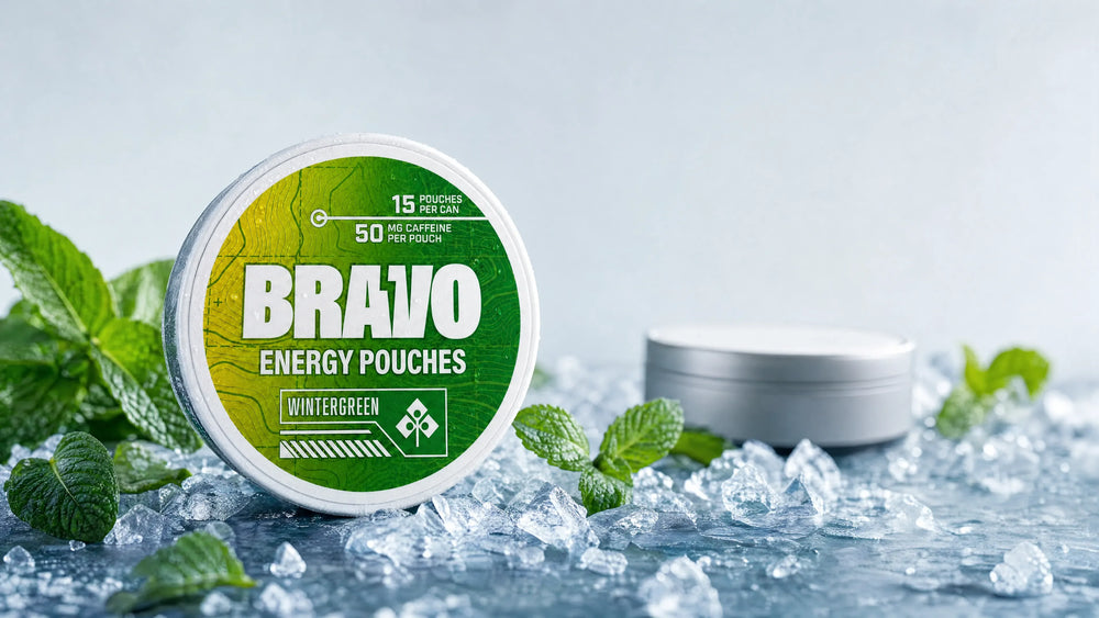 Bravo Wintergreen energy pouch can in sharp focus with mint leaves and ice, one small unbranded soft-focus competitor tin in the background
